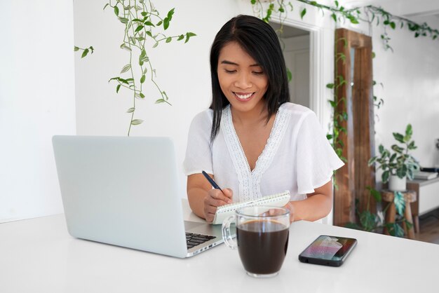 Mujer joven usando laptop y tomando una taza de café