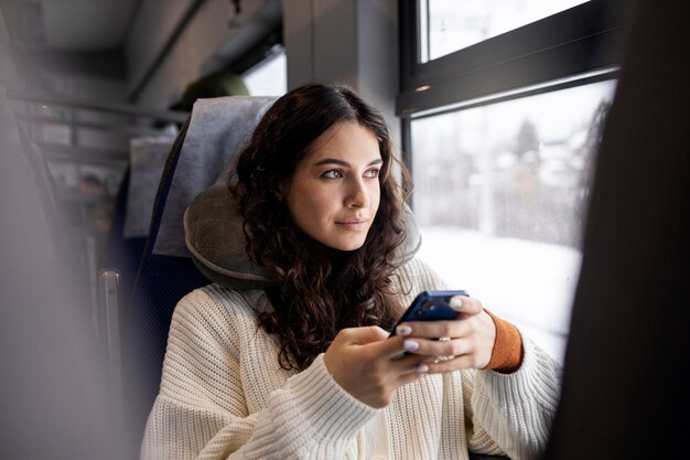 Mujer joven usando su teléfono inteligente mientras viaja en tren
