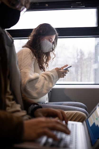 Foto gratuita mujer joven usando su teléfono inteligente mientras viaja en tren