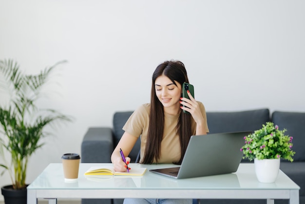 mujer joven, utilizar, teléfono móvil, y, computador portatil, en casa