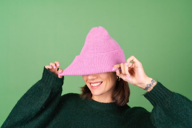 Foto gratuita mujer joven en verde en un cálido suéter acogedor y un sombrero rosa lindo sonriendo
