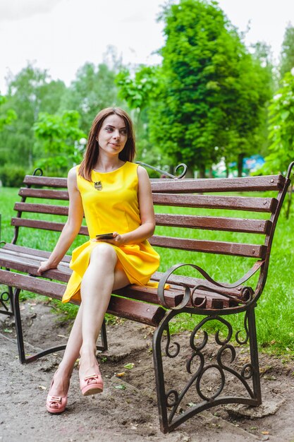 Mujer joven vestida de amarillo con un teléfono inteligente en la mano