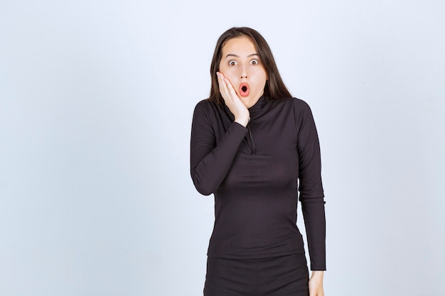 Mujer joven vestida de negro se ve aterrorizada y asustada