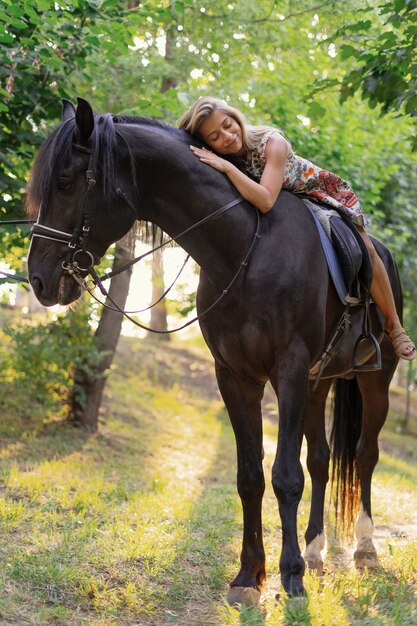 Mujer joven en un vestido colorido brillante montando un caballo negro