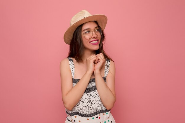 Mujer joven en vestido gris con sombrero y gafas