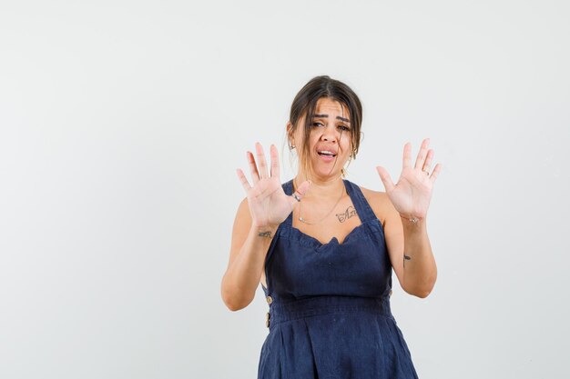 Mujer joven en vestido mostrando gesto de parada y mirando molesto