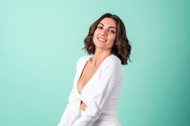 Mujer joven en un vestido de noche blanco sobre verde claro con maquillaje rosa brillante