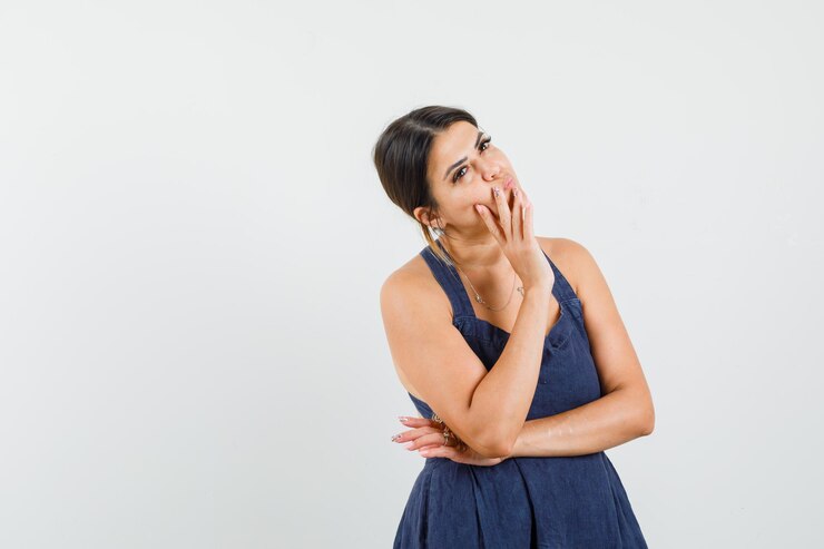 Foto gratuito mujer joven en vestido de pie en pose de pensamiento y mirando sensible