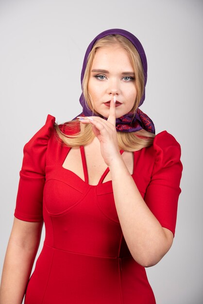 Mujer joven en vestido rojo dando un trato silencioso.