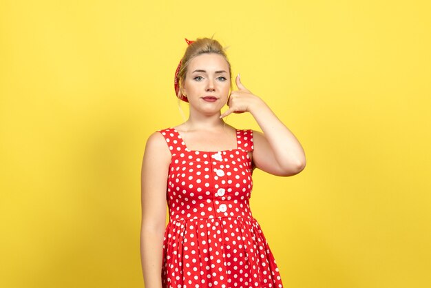 Mujer joven en vestido rojo de lunares llamando plantean en amarillo