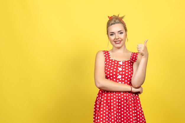 mujer joven en vestido rojo de lunares posando en amarillo