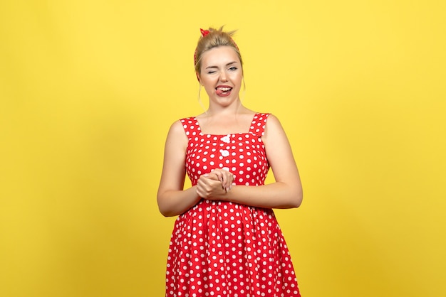 mujer joven en vestido rojo de lunares posando en amarillo