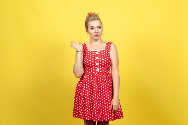 mujer joven en vestido rojo de lunares posando en amarillo