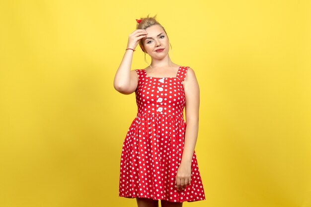 mujer joven en vestido rojo de lunares posando en amarillo