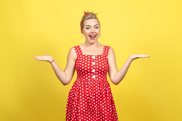 mujer joven en vestido rojo de lunares posando en amarillo