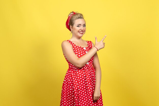 mujer joven en vestido rojo de lunares posando en amarillo