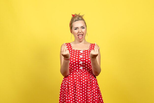 mujer joven en vestido rojo de lunares posando en amarillo