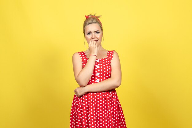 mujer joven en vestido rojo de lunares posando en amarillo