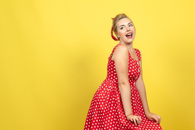 mujer joven en vestido rojo de lunares posando en amarillo