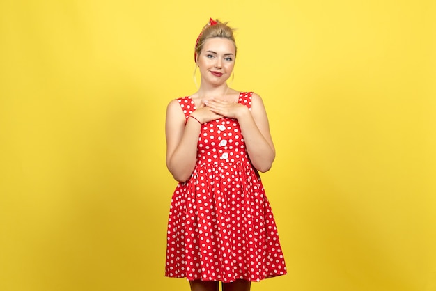 mujer joven en vestido rojo de lunares posando en amarillo