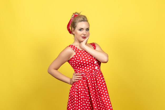 Foto gratuita mujer joven en vestido rojo de lunares posando en amarillo