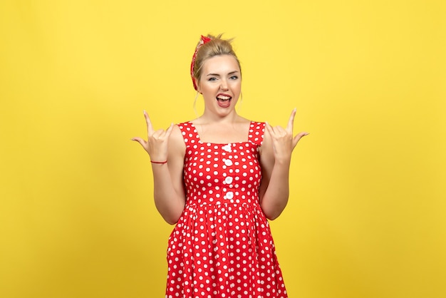 Foto gratuita mujer joven en vestido rojo de lunares posando emocionalmente en amarillo