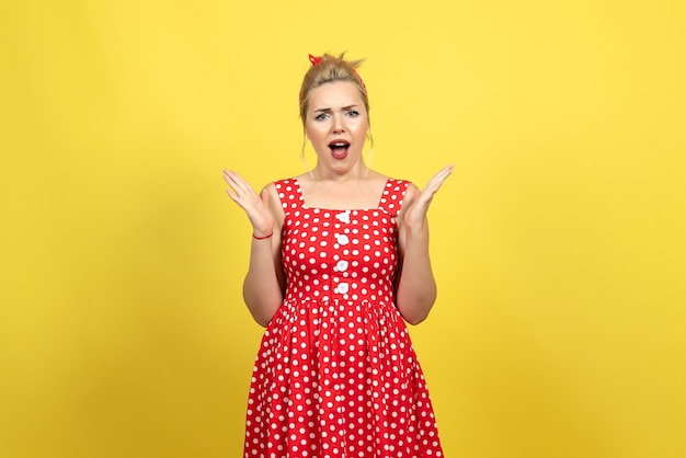 mujer joven en vestido rojo de lunares sobre amarillo