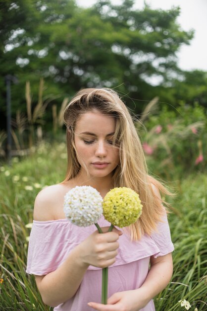 Mujer joven en vestido sosteniendo flores en la mano