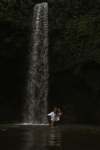 mujer joven viaja por la isla tomando fotos en una cascada