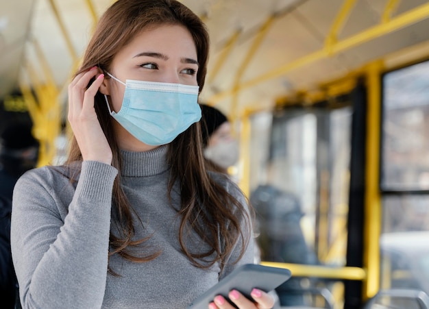 Foto gratuita mujer joven viajando en autobús urbano con smartphone