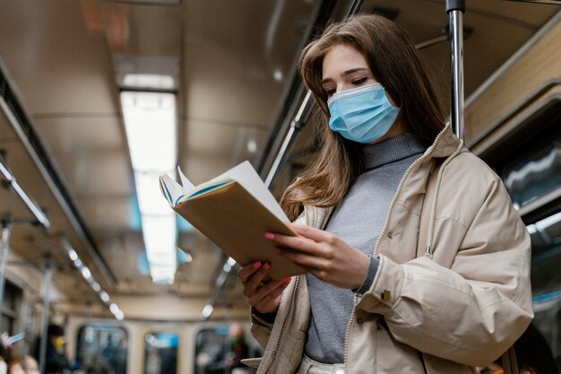 Mujer joven viajando en metro leyendo un libro