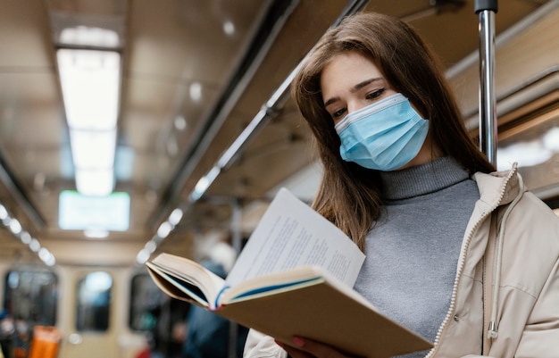 Foto gratuita mujer joven viajando en metro leyendo un libro