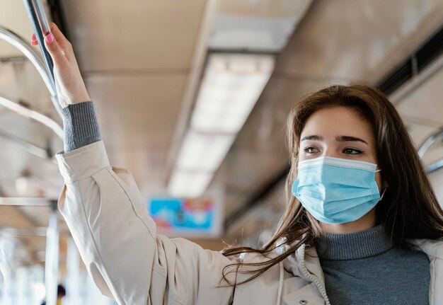 Mujer joven viajando en metro con una mascarilla quirúrgica