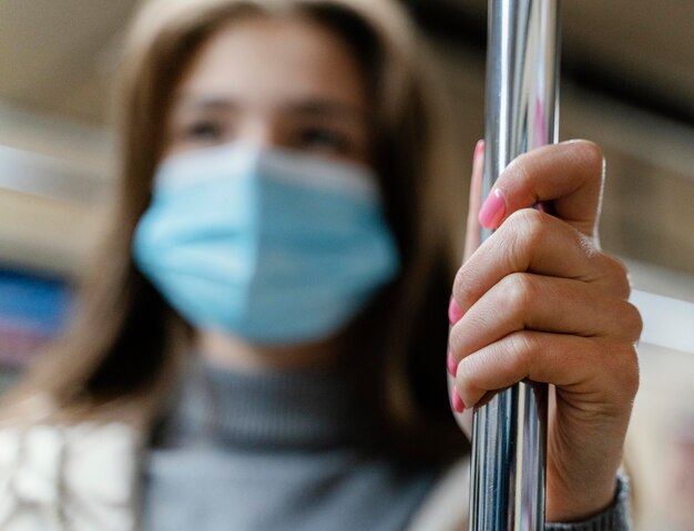 Mujer joven viajando en metro con una mascarilla quirúrgica