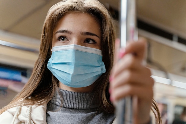 Mujer joven viajando en metro con una mascarilla quirúrgica