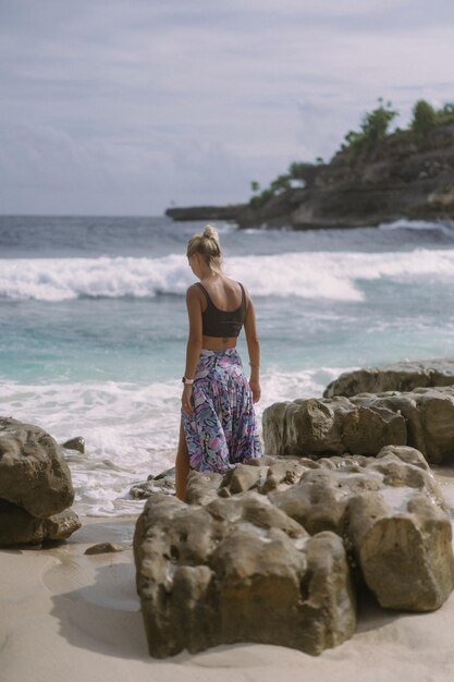 Mujer joven en un viaje. Viajero en una roca junto al océano.