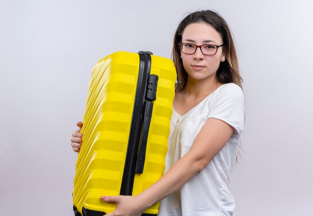 Mujer joven viajero en camiseta blanca con maleta