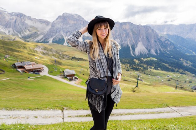 Mujer joven viajero con sombrero y mochila disfrutando de increíbles vistas a la montaña