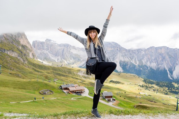 Mujer joven viajero con sombrero y mochila disfrutando de increíbles vistas a la montaña