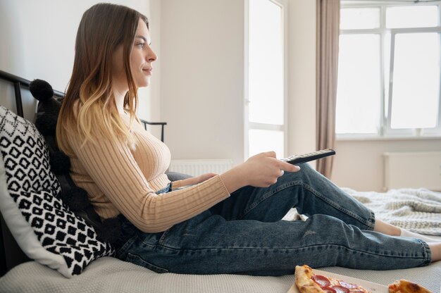 Mujer joven viendo la televisión en la cama