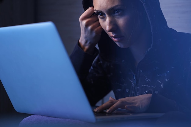 Mujer joven violando el sistema de seguridad de la red y robando datos de la computadora portátil por la noche