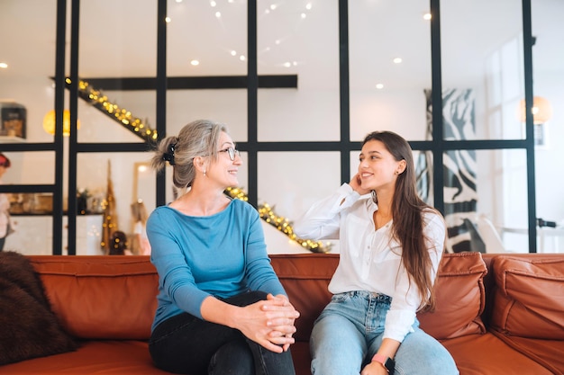 Foto gratuita mujer joven visitando a la abuela en casa, las mujeres hablan