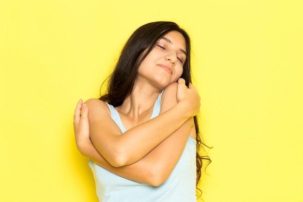 Foto gratuita una mujer joven de vista frontal en camisa azul posando y abrazándose a sí misma