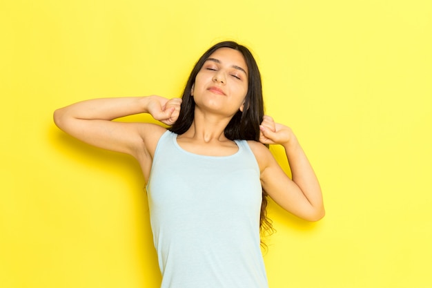 Una mujer joven de vista frontal en camisa azul posando y estornudos en el fondo amarillo pose de niña modelo belleza joven