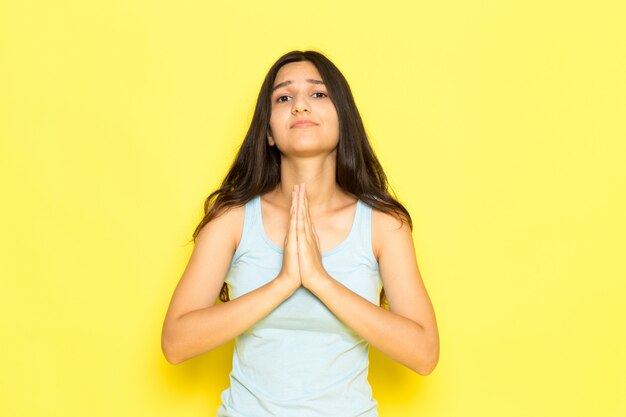 Una mujer joven de vista frontal en camisa azul posando con expresión de oración