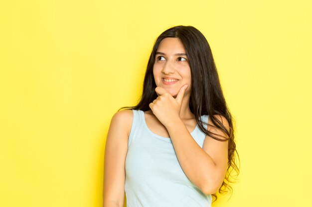 Una mujer joven de vista frontal en camisa azul posando con expresión de pensamiento