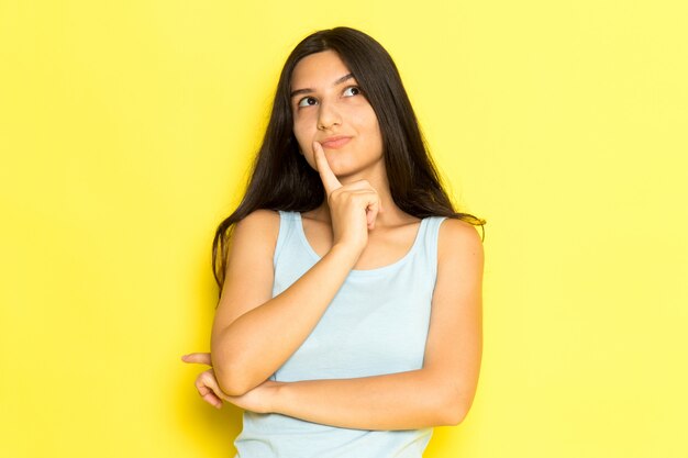 Una mujer joven de vista frontal en camisa azul posando con expresión de pensamiento