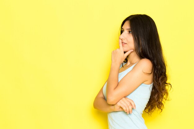 Una mujer joven de vista frontal en camisa azul posando con expresión de pensamiento