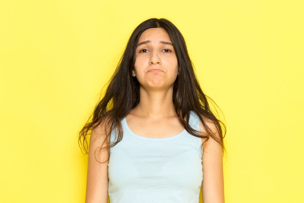 Una mujer joven de vista frontal en camisa azul posando con expresión triste