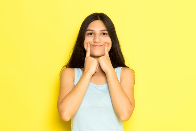 Una mujer joven de vista frontal en camisa azul posando sosteniendo su boca haciendo una sonrisa